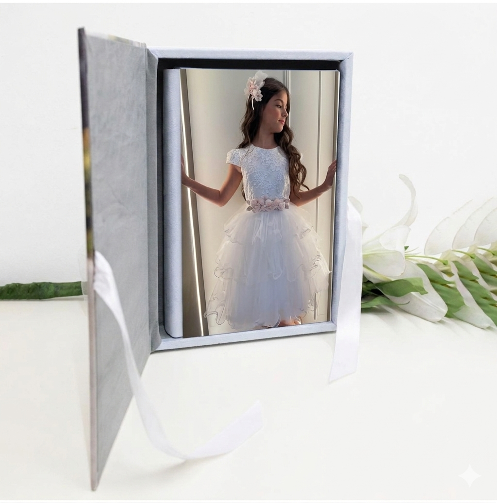 Dettaglio del Kit Mary: album fotografico con copertina in tela canvas personalizzata con il ritratto di una bambina, chiuso lateralmente da un elegante nastrino di raso bianco legato a fiocco.